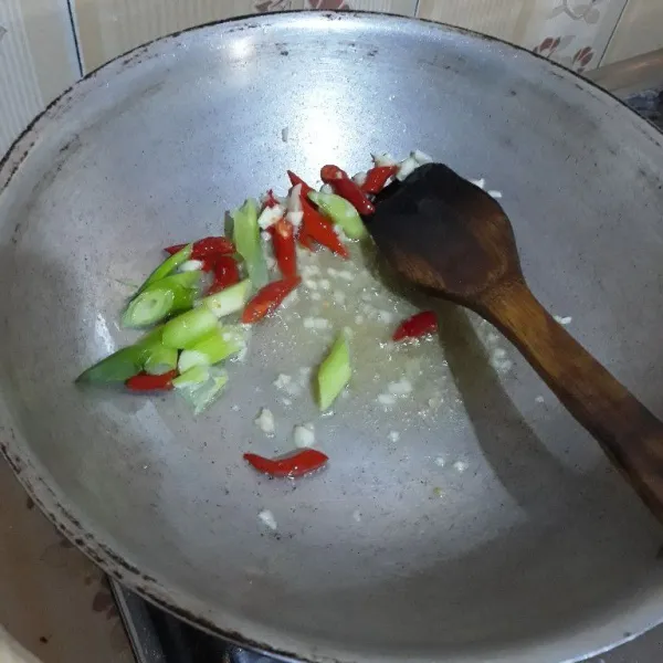 Tumis bawang putih, cabe merah keriting dan batang daun bawang hingga harum dan layu.