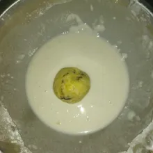 Celupkan banana bomb ke dalam adonan pencelup, angkat lalu gulingkan ke dalam tepung roti.