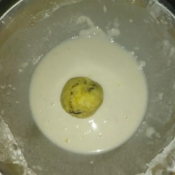 Celupkan banana bomb ke dalam adonan pencelup, angkat lalu gulingkan ke dalam tepung roti.