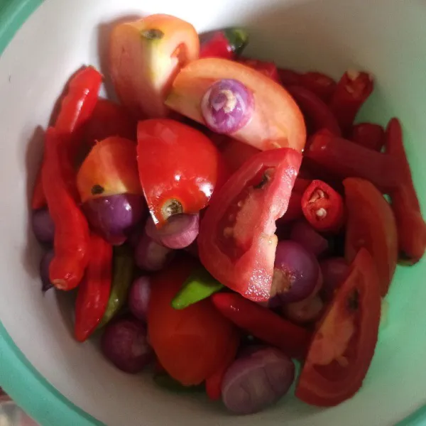 Potong-potong bawang merah, bawang putih, cabai, dan tomat supaya lebih mudah menghaluskannya
