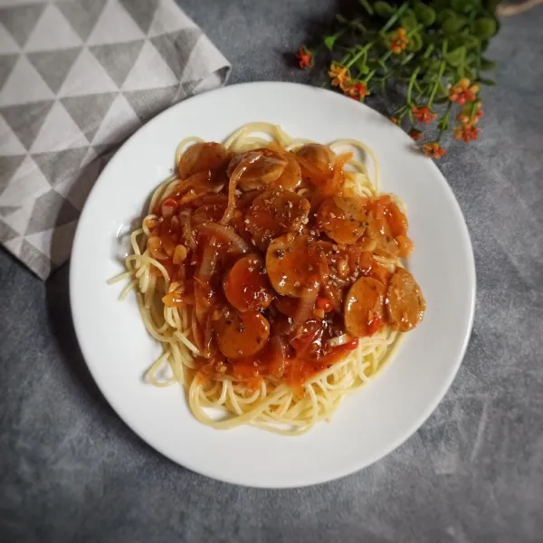 Tata spaghetti di atas piring kemudian tuang saus di atasnya dan taburi dengan oregano kering.