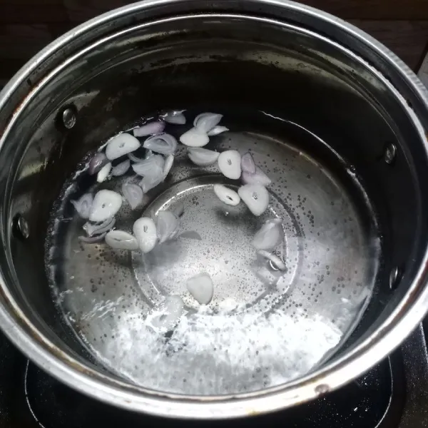 Didihkan air di panci. Masukkan irisan bawang merah dan bawang putih.