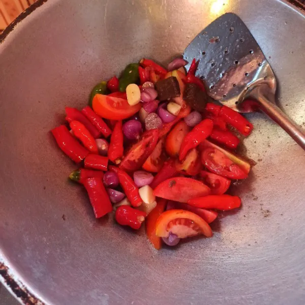 Panaskan minyak goreng secukupnya, kemudian masukkan bawang merah, bawang putih, cabai, tomat, dan terasi, lalu goreng hingga layu dan matang
