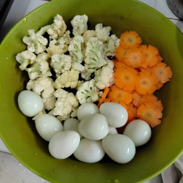 Kupas kulit telur puyuh, potong kecil wortel dan bersihkan kembang kol.