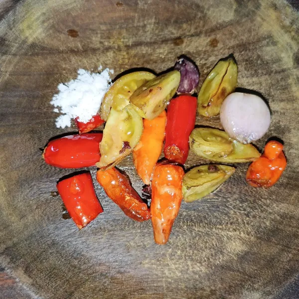 Goreng tomat merah, bawang merah, cabai rawit dan cabai merah sampai layu, lalu pindahkan ke dalam cobek dan tambahkan garam, gula pasir dan kaldu jamur.