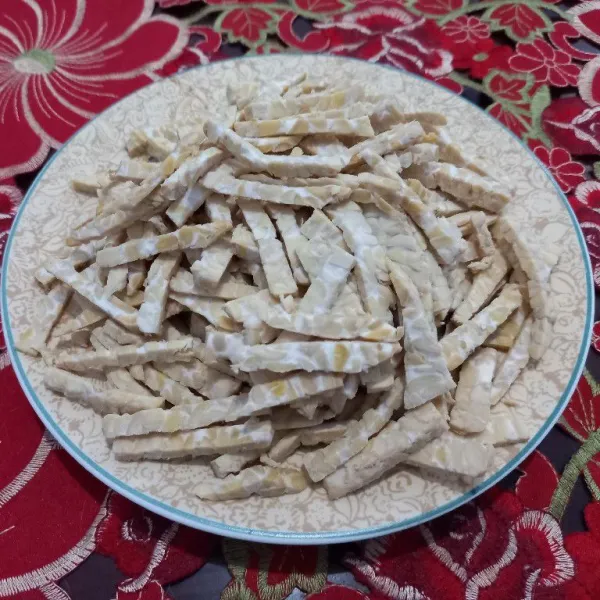 Potong tempe menjadi empat bagian, lalu iris tipis-tipis