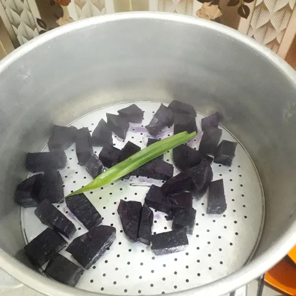 Siapkan kukusan. Didihkan air di dalam kukusan. Masukkan ubi ungu bersama daun pandan. Kukus hingga lunak