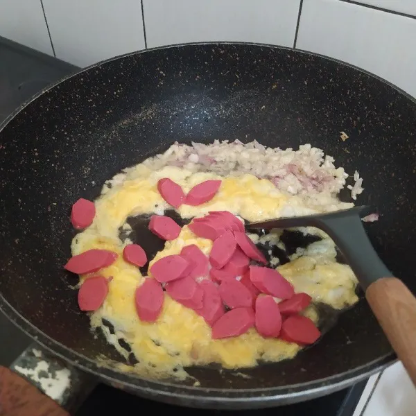 Masukkan kocokan telur dan irisan sosis lalu tumis hingga matang.