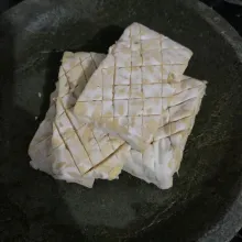 Potong tempe dan garit-garit lalu rendam dengan larutan air garam.