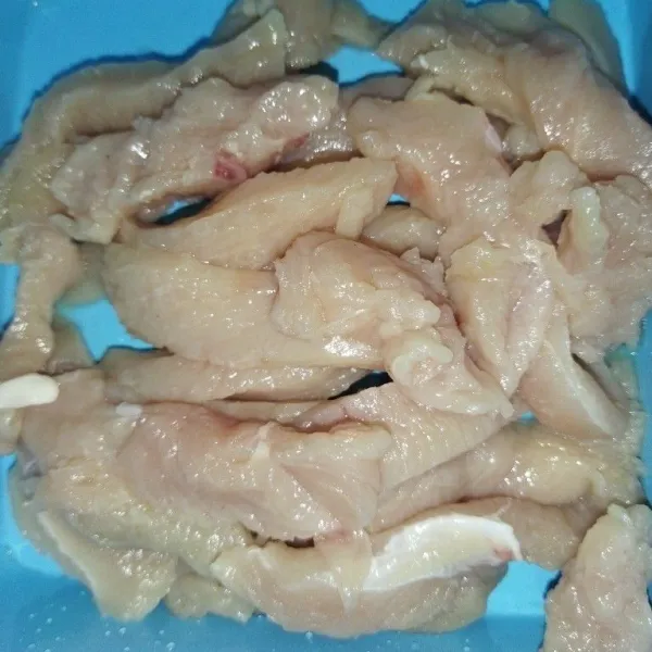 Siapkan daging ayam yang sudah dibilas, lalu potong agak pipih memanjang.