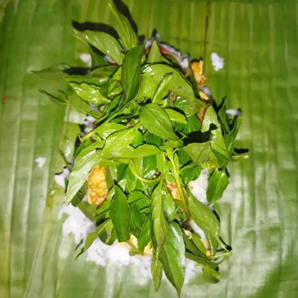 Tata daun kemangi di atasnya, bungkus dengan daun pisang, lalu sematkan dengan tusuk lidi.