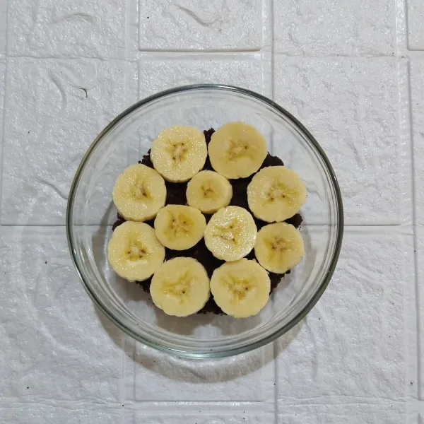 Potong-potong pisang sesuai selera dan tata diatas brownies.