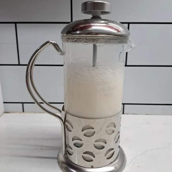 Masukkan susu ke dalam french press. Kocok sampai berbuih banyak.