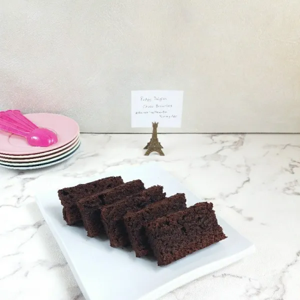 Diamkan hingga suhu ruang, potong Fudgy Belgian Choco Brownies sesuai selera, beri cokelat leleh secukupnya.