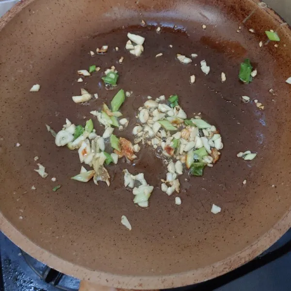 Tumis bawang putih dan daun bawang dengan canola oil sampai harum.