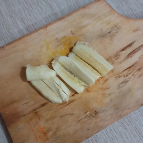Potong pisang jadi 2 bagian.