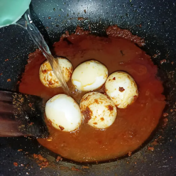 Masukkan telur rebus dan aduk rata, lalu tuang air.