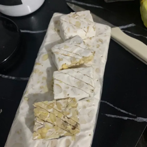 Siapkan tempe potong garit rendam garam.