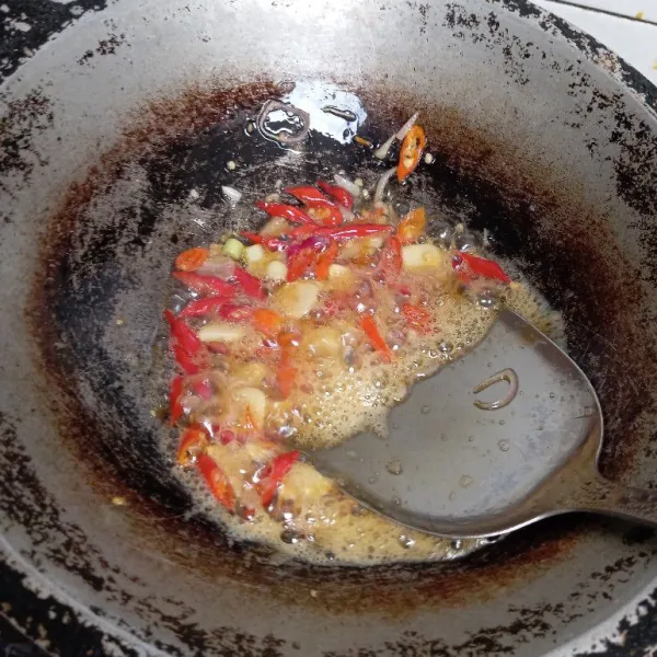 Panaskan minyak di wajan. Masukkan irisan cabai, bawang merah, dan bawang putih, tumis sampai matang