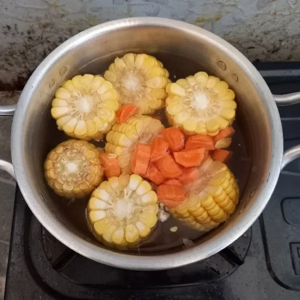 Masukkan jagung manis dan wortel ke dalam rebusan air
