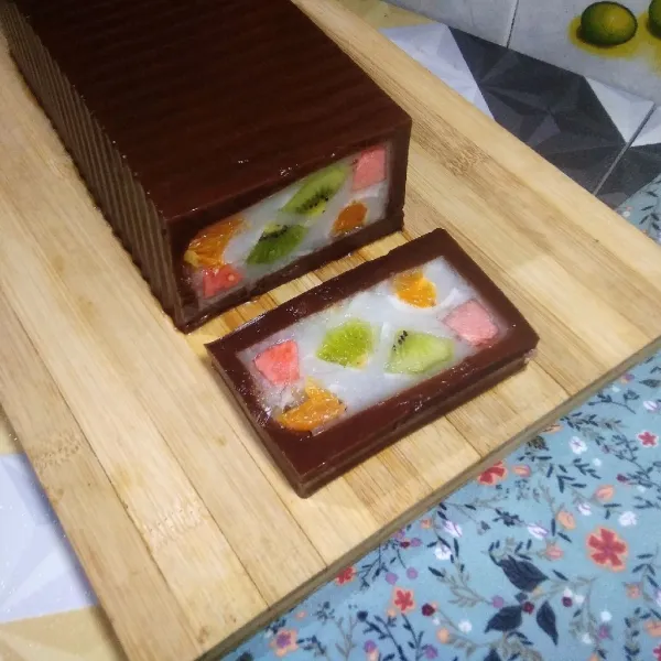 Keluarkan puding buah lapis cokelat dari loyang. Potong-potong, lalu simpan dalam wadah saji dan siap untuk di sajikan.