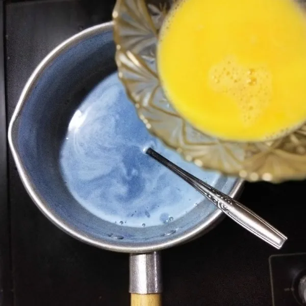 Tambahkan telur sambil diaduk hingga terbentuk motif serat telur. Tambahkan juga selasih dan pasta vanili, lalu aduk rata. Koreksi rasa, matikan api sambil tetap diaduk hingga uap panas hilang.