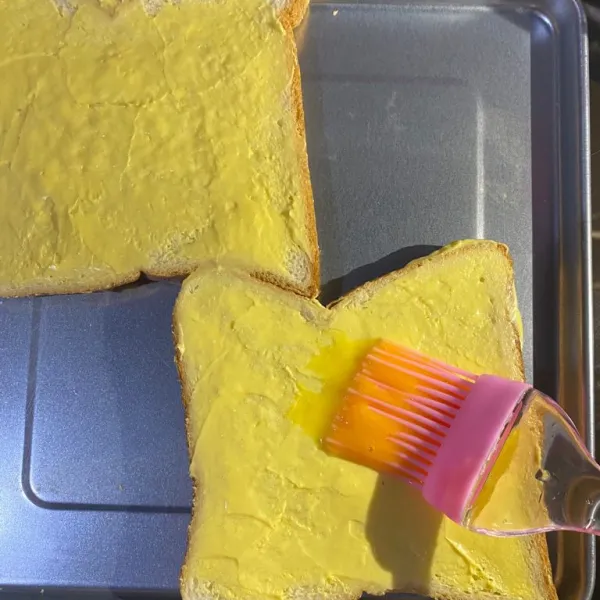 Siapkan 2 lembar roti tawar, olesi dengan margarin dan kuning telur.