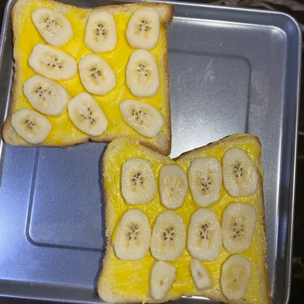 Lalu tata pisang yang sudah di iris tipis di atas roti tawar.