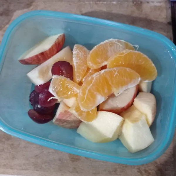 Cuci bersih buah, kemudian potong-potong anggur dan apel, buang bijinya, kupas jeruk lalu buang serabutnya.
