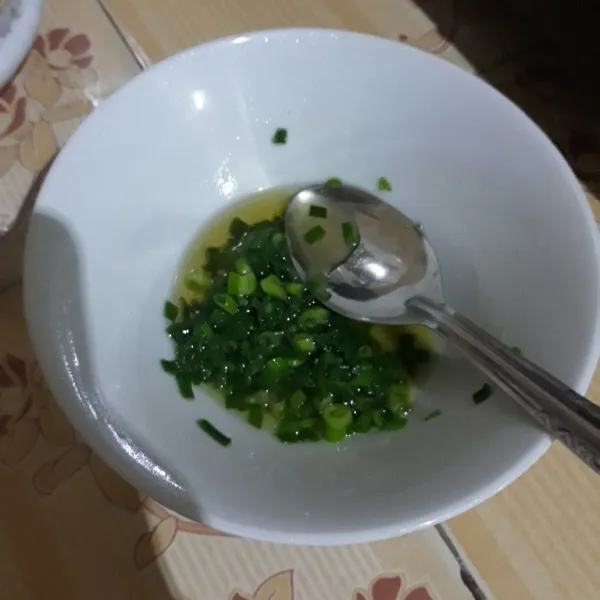 Tambahkan garam dan kaldu bubuk lalu siram dengan minyak panas dan tambahkan minyak wijen, aduk rata.