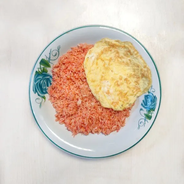 Sajikan nasi goreng dengan telur dadar.