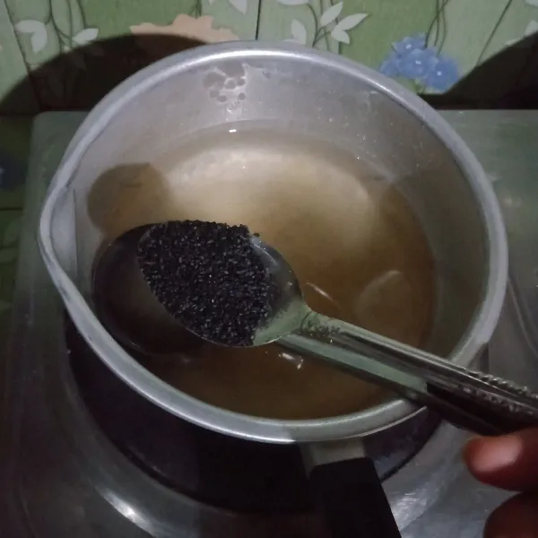 Untuk puding bening, masukkan bubuk agar-agar plain, air, susu kental manis, biji selasih, dan gula pasir. Masak hingga mendidih sambil diaduk-aduk.