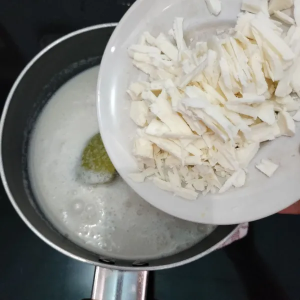 Kemudian, masukkan roti tawar yang sudah dihaluskan ke dalam panci dan tambahkan cokelat putih batang. Aduk sampai rata.