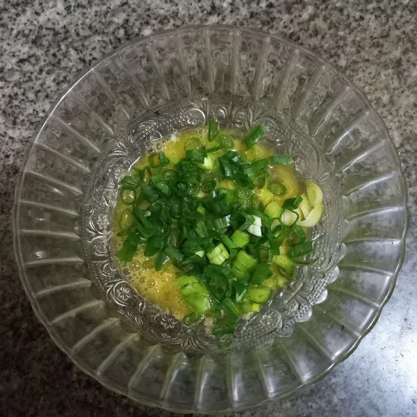 Masukkan irisan bawang daun ke dalam kocokan telur.