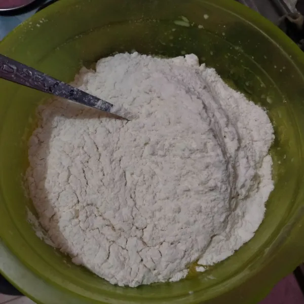 Masukkan tepung terigu, aduk hingga menjadi gumpalan. Apabila adonan terasa kering, tambahkan air sampai adonan lembab.