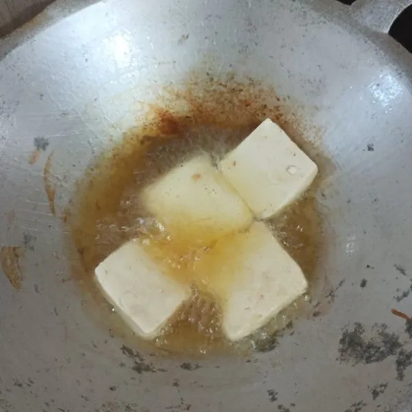 Tiriskan tahu, langsung goreng ke wajan berisi minyak panas,