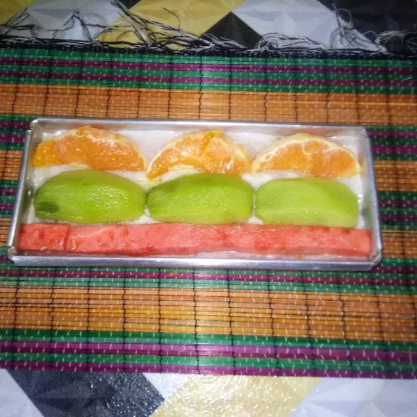 Tambahkan dan tata kembali potongan buah di atas adonan yang telah padat secara selang- seling dari posisi buah pertama.