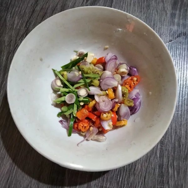 Iris tipis cabai rawit, bawang merah, daun jeruk dan serai bumbui garam dan kaldu bubuk. Panaskan minyak bisa pakai minyak bekas goreng ikan.