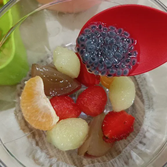 Siapkan wadah, tata buah strawberry, anggur, jeruk, melon, dan semangka dalam wadah, lalu tambahkan biji selasih secukupnya.