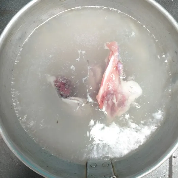 Rebus air. Masukkan tulang ayam yang sudah dipotong kecil dan tunggu hingga mendidih, buang buih kotoran ayam di atasnya.