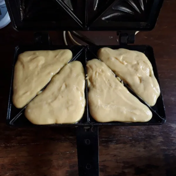 Panaskan cetakan sadwich maker. Olesi tipis margarin, tuang adonan hingga penuh.
