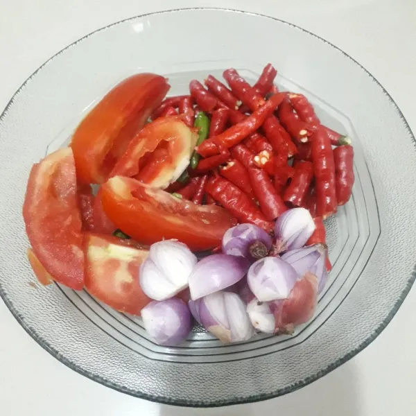 Siapkan bahan sambal, kupas dan iris-iris bawang merah. Cuci bersih lalu potong-potong tomat merah dan cabe.