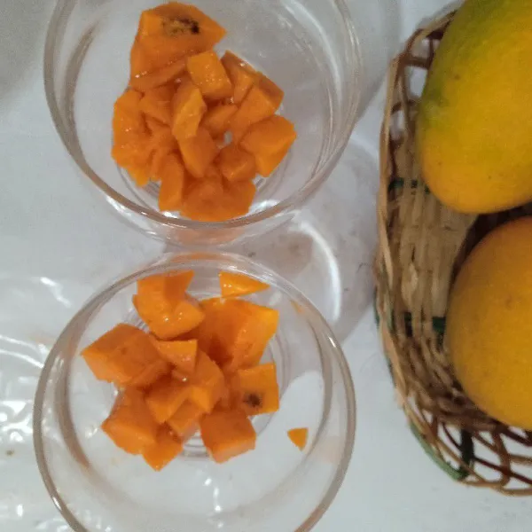 Kupas mangga, potong bentuk kotak dadu, masukkan ke gelas saji, hancurkan dengan sendok.