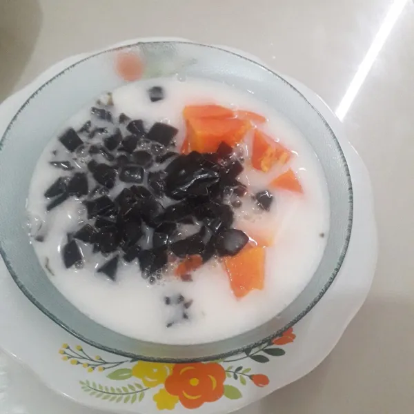 Tuangkan santan yang telah direbus ke dalam mangkuk berisi pepaya dan cincau.