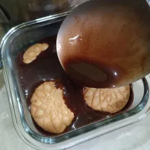 Siapkan wadah, tata biskuit kelapa, lalu guyur dengan puding coklat, tuang sekitar ⅓ bagian, tunggu hingga set.