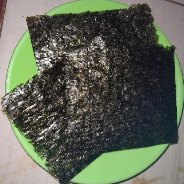 Ambil satu lembar nori lalu gunting menjadi 4 bagian.