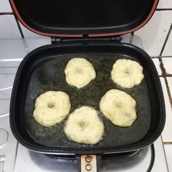 Goreng donat di minyak panas api sedang cenderung kecil. Cukup sekali balik.