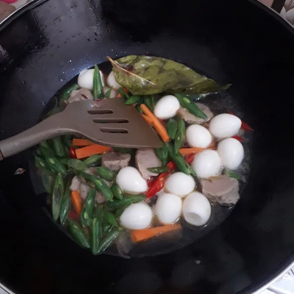 Masukkan buncis, wortel, bakso dan telur puyuh. Aduk-aduk. Tambahkan air. Masak hingga air mendidih.