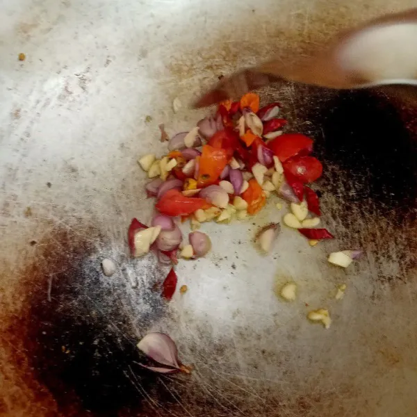Tumis bumbu iris bawang merah, bawang putih, cabai merah dan tomat menggunakan minyak zaitun.