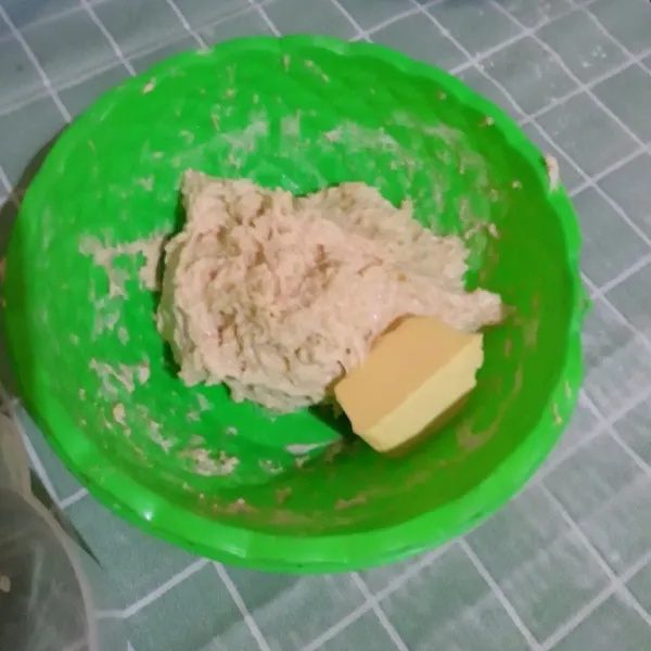 Tambahkan mentega dan campurkan menggunakan tangan, jika adonan terlalu lengket tambahkan tepung terigu sedikit demi sedikit. Uleni hingga tidak lengket.